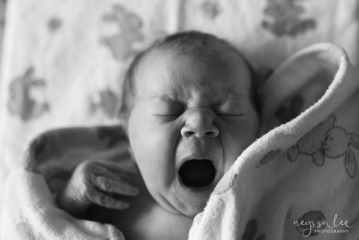 Newborn baby girl yawning in hospital swaddle