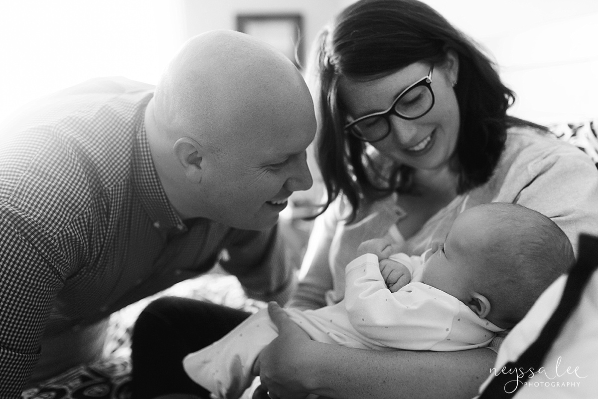 Mom and Dad smiling at baby during newborn photos