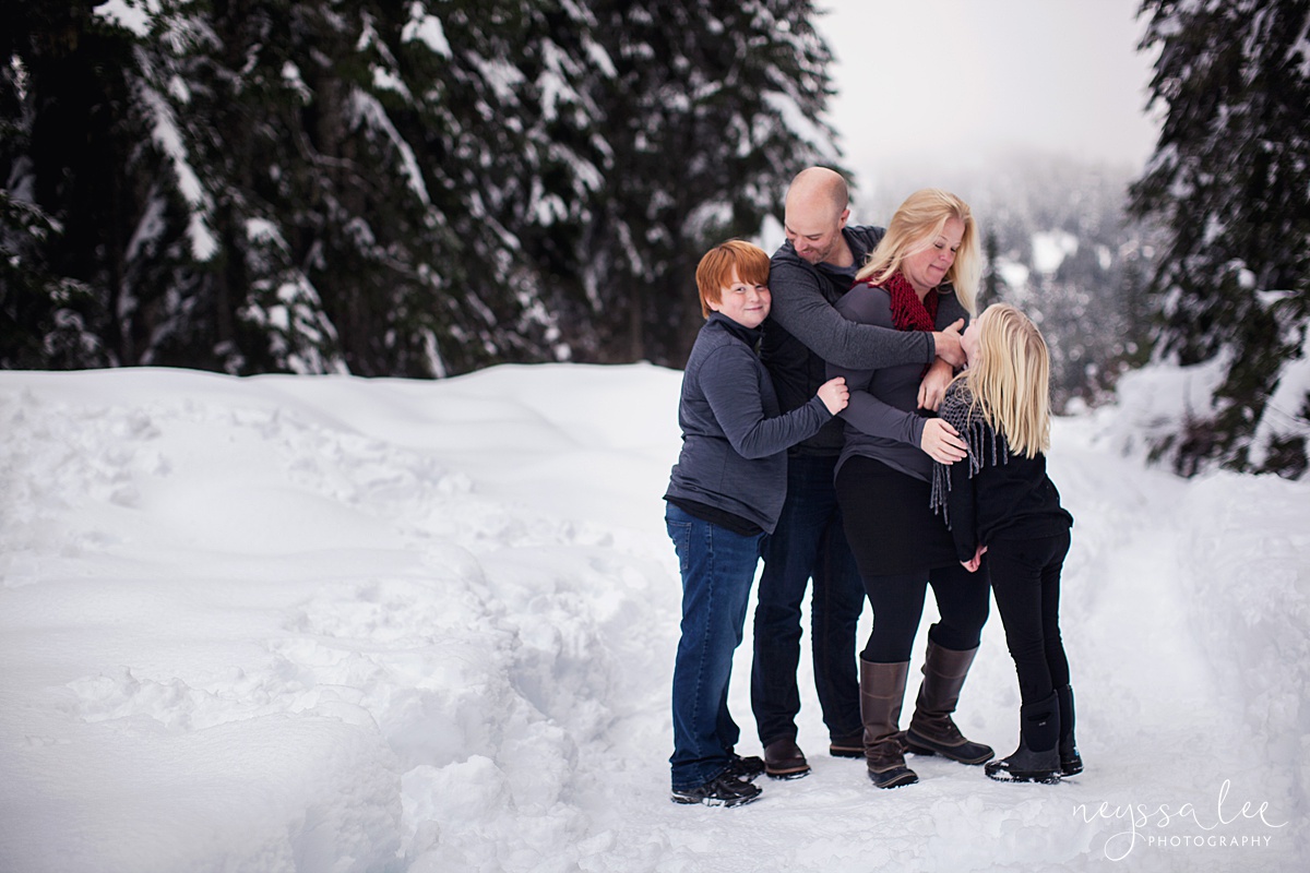 Family of 4 take family photos at Snoqualmie Pass in the snow
