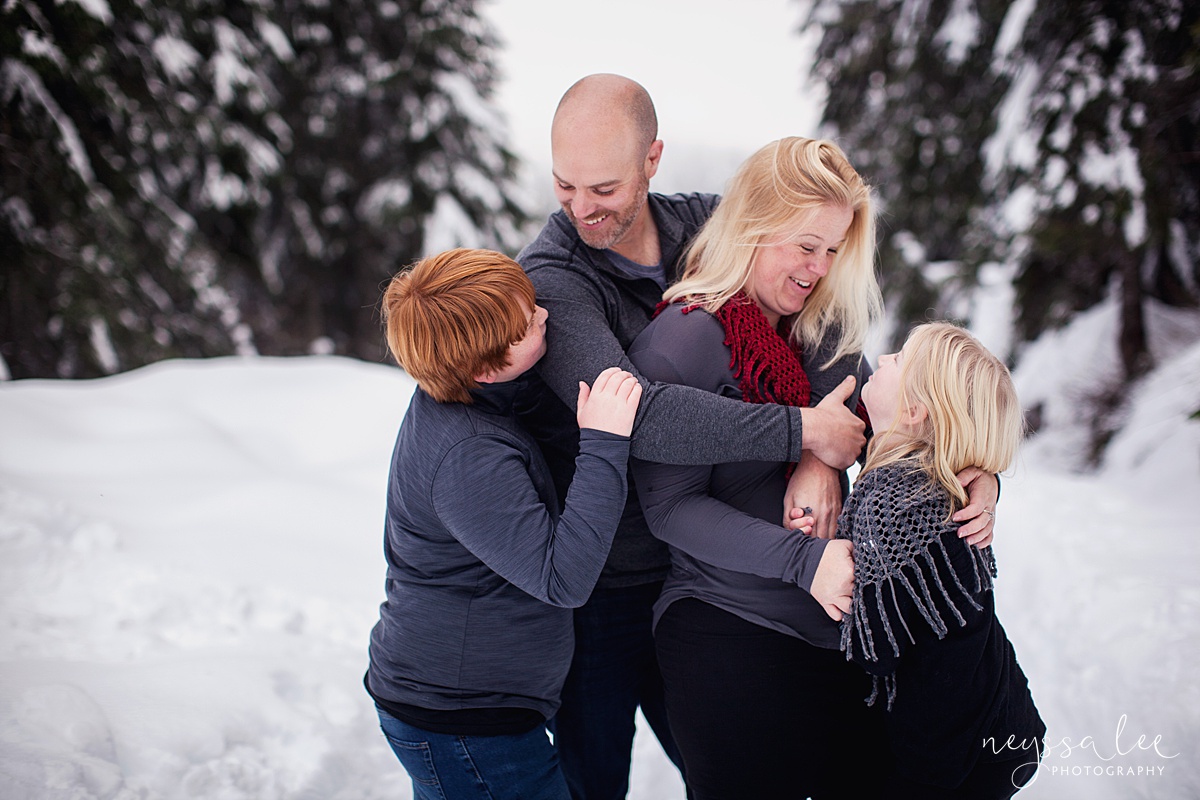 Family of 4 bundle up in the snow for family photos