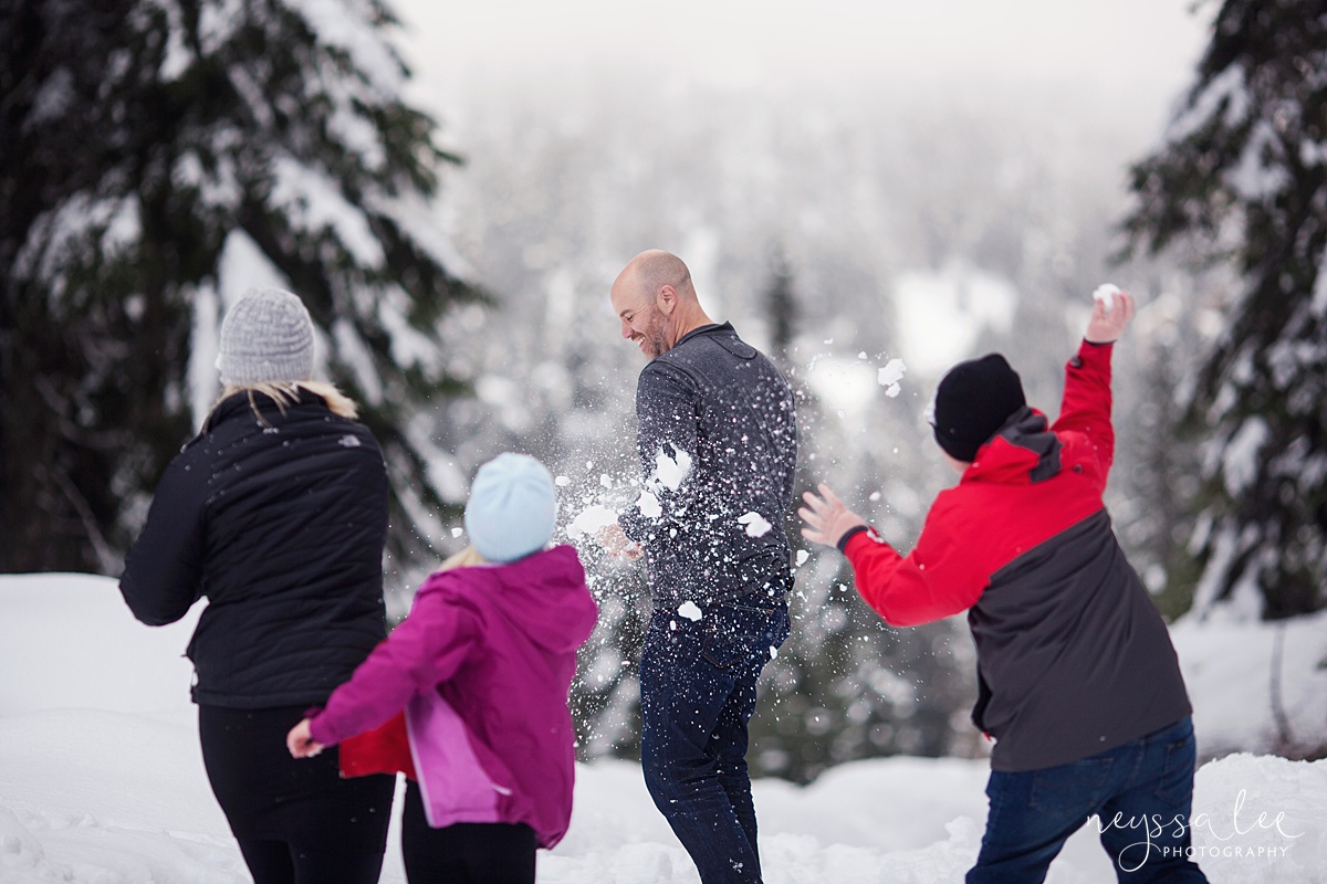 Family snowball fight during family photos at Snoqualmie Pass, kids throwing snow at father