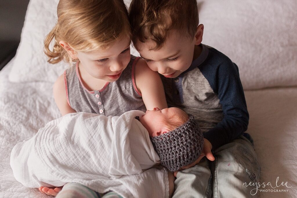 Brother and sister holding newborn baby sister during Snoqualmie newborn photo session