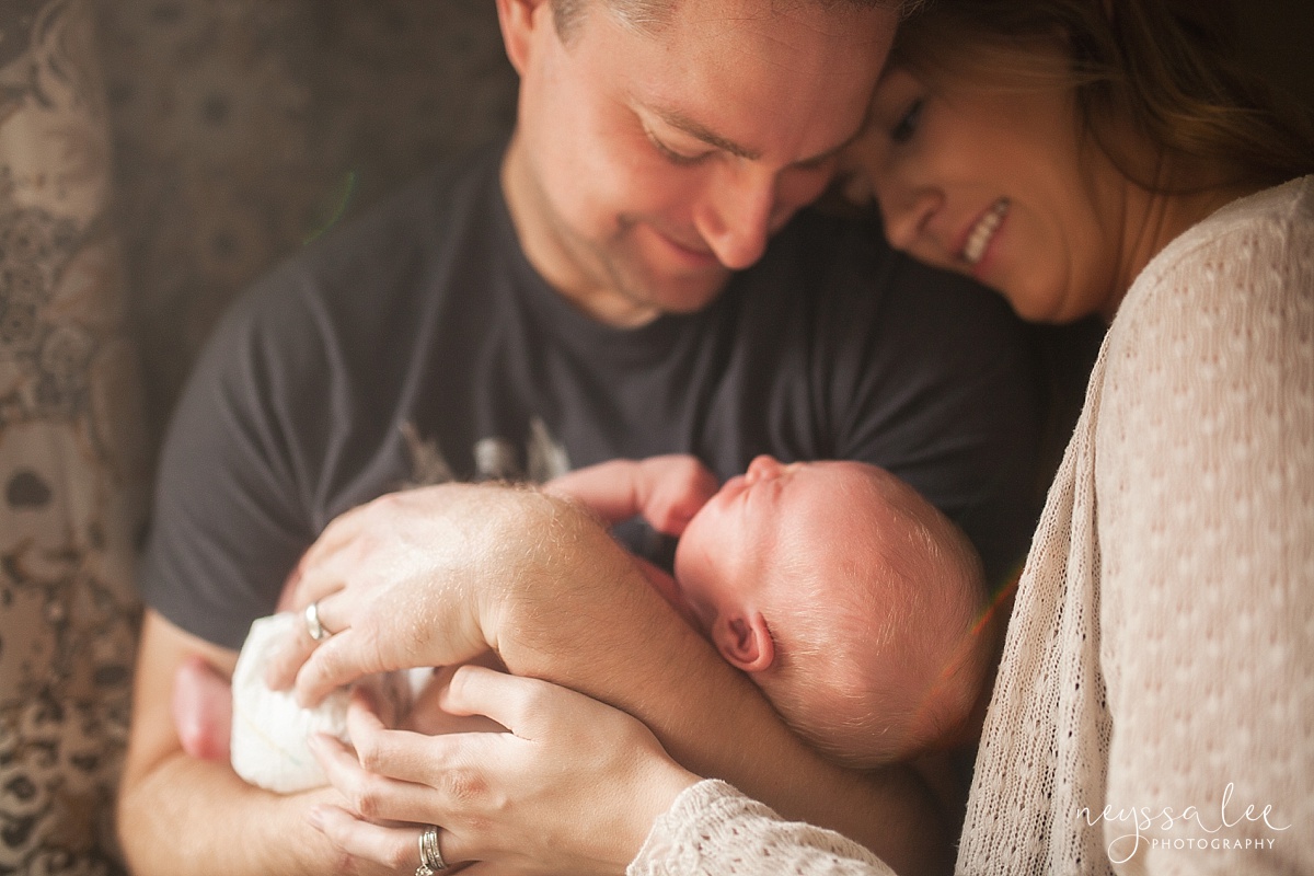 Newborn baby boy photographed in warm light, cradled in fathers arms
