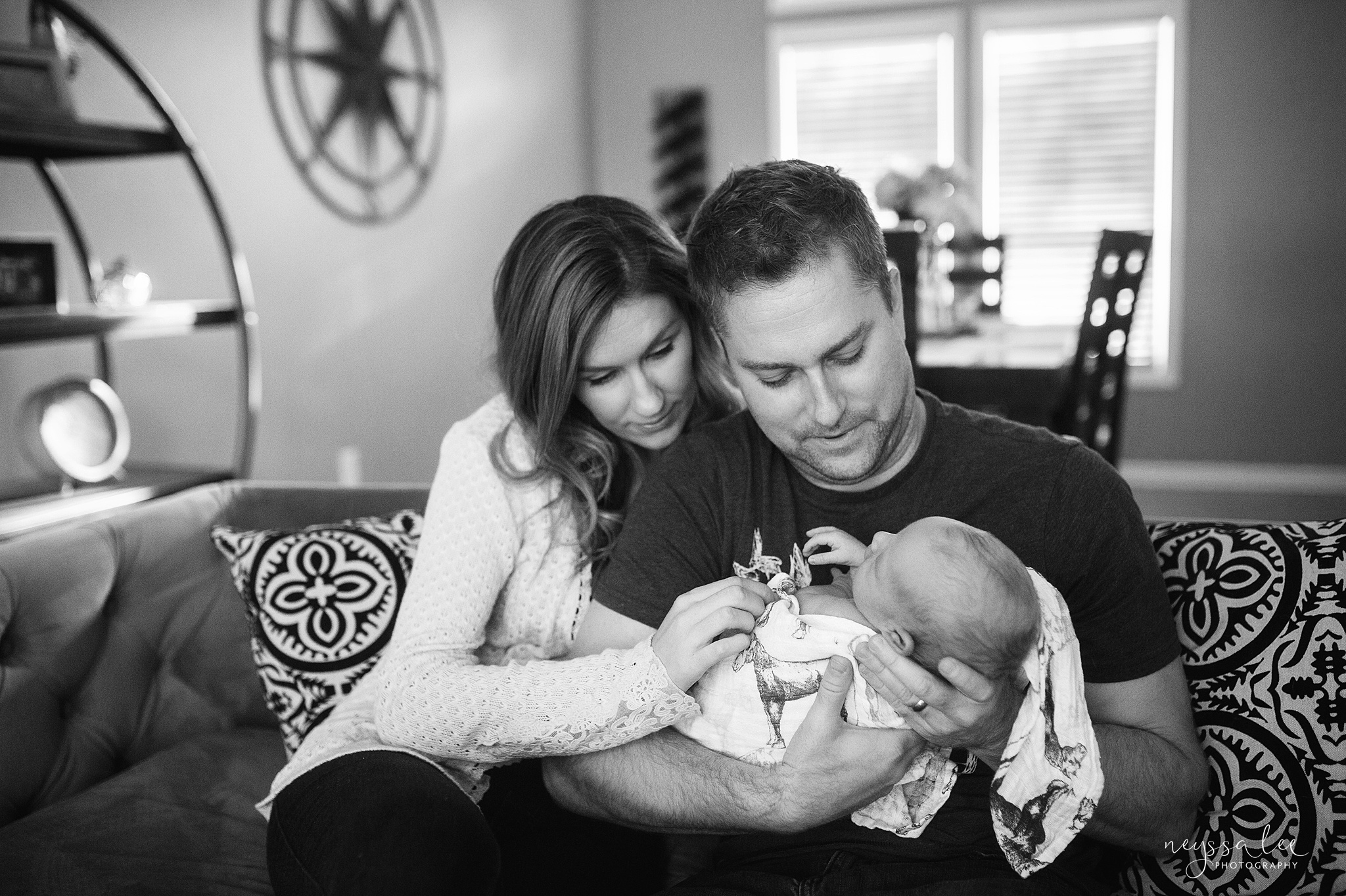 Newborn baby boy photography in  black and white. Mom and Dad holding baby on couch