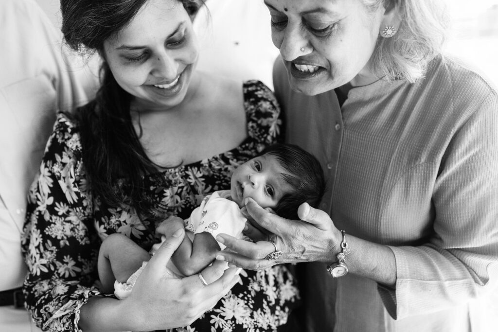 Mother and grandmother with newborn baby girl during lifestyle in home newborn photo session