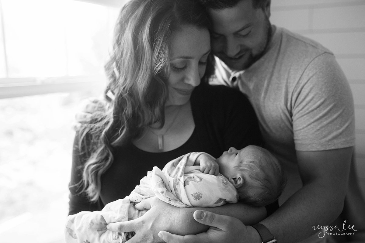 Black and white image of mom and dad admiring newborn baby