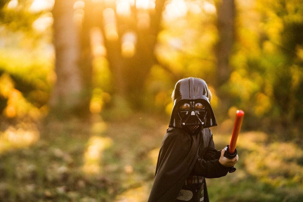 Boy swinging light saber for photo tips example in Darth Vader costume