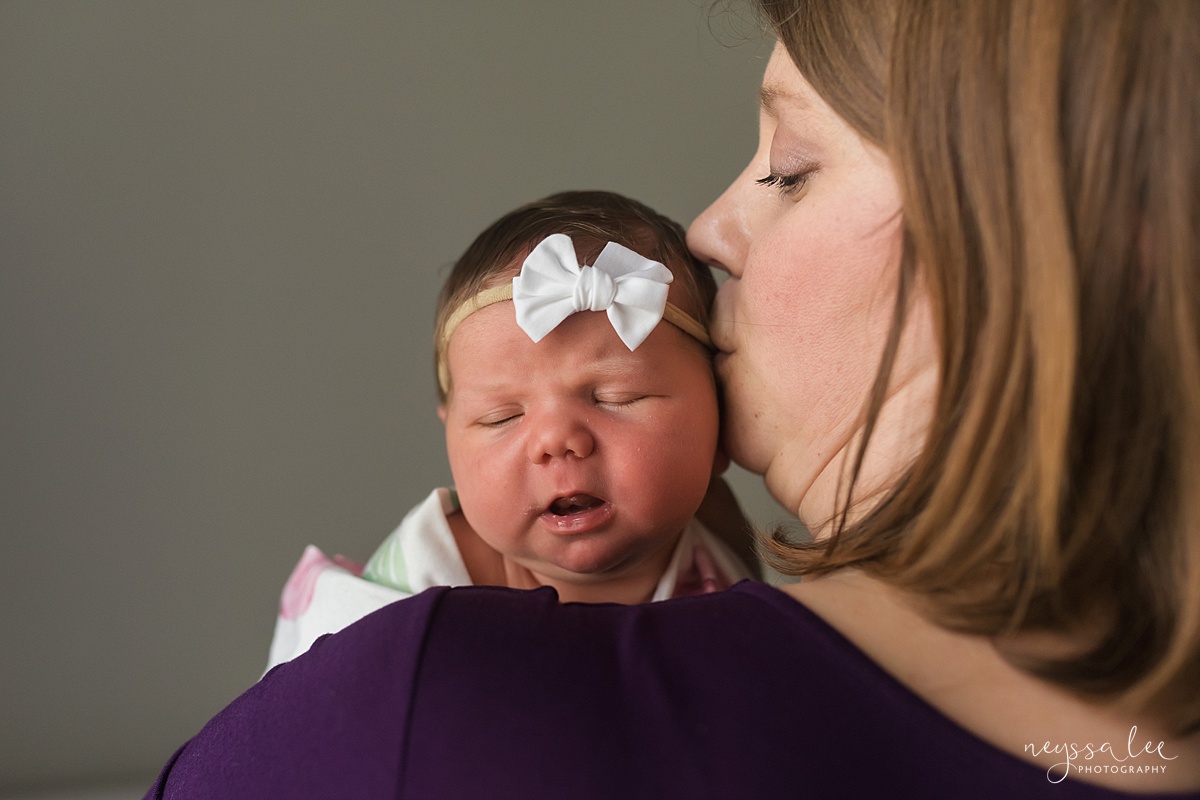 Photo of mom kissing newborn baby cheek