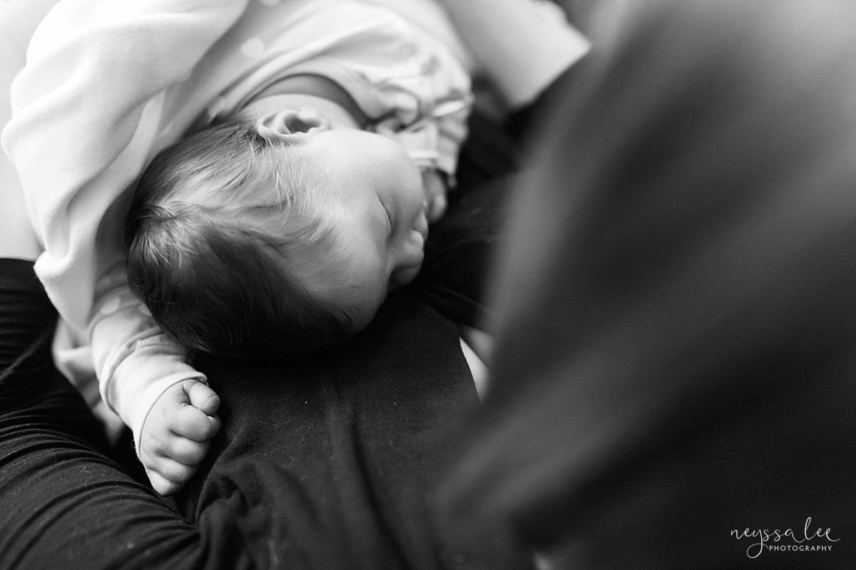  black and white photo of newborn asleep against moms chest