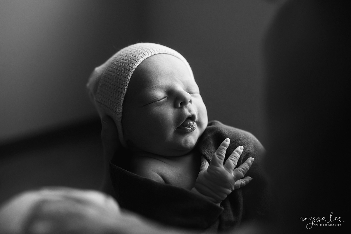 Black and white photo of newborn boy sticking out tongue during Issaquah Fresh 48 photo session