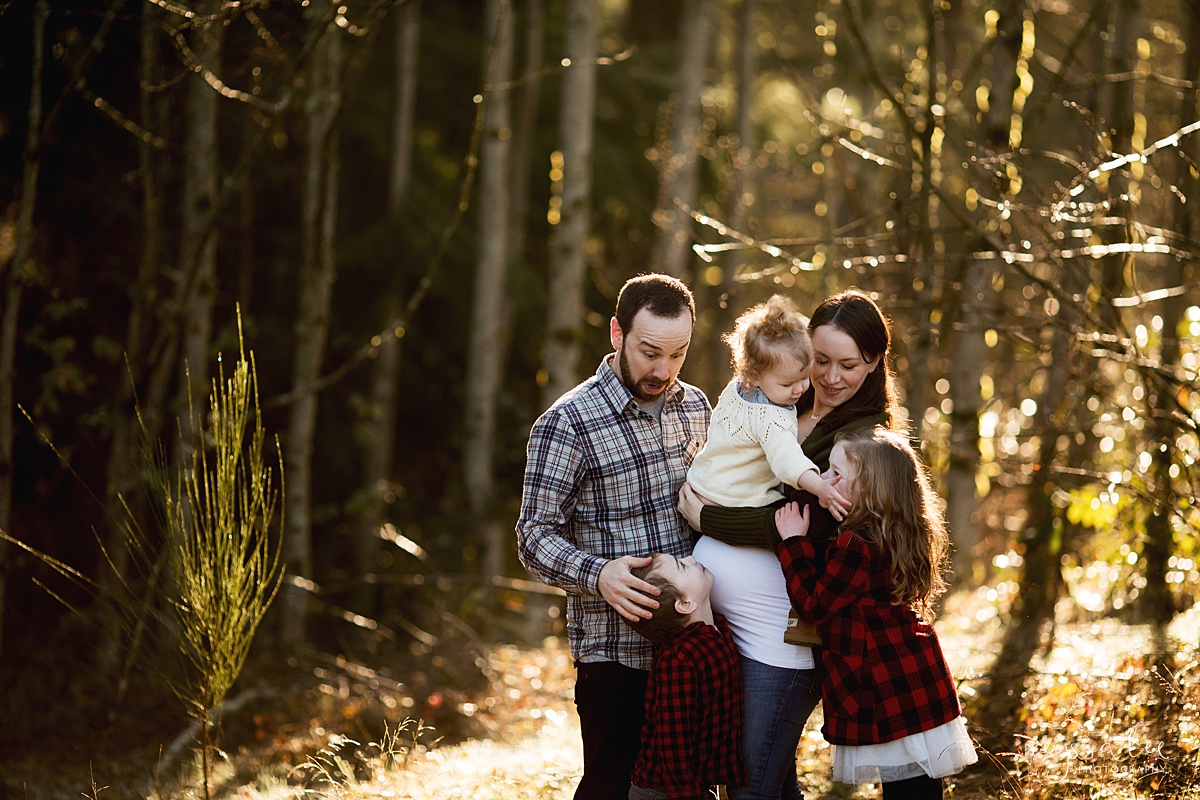 Maternity photo of family of five cuddled together in beautiful back light
