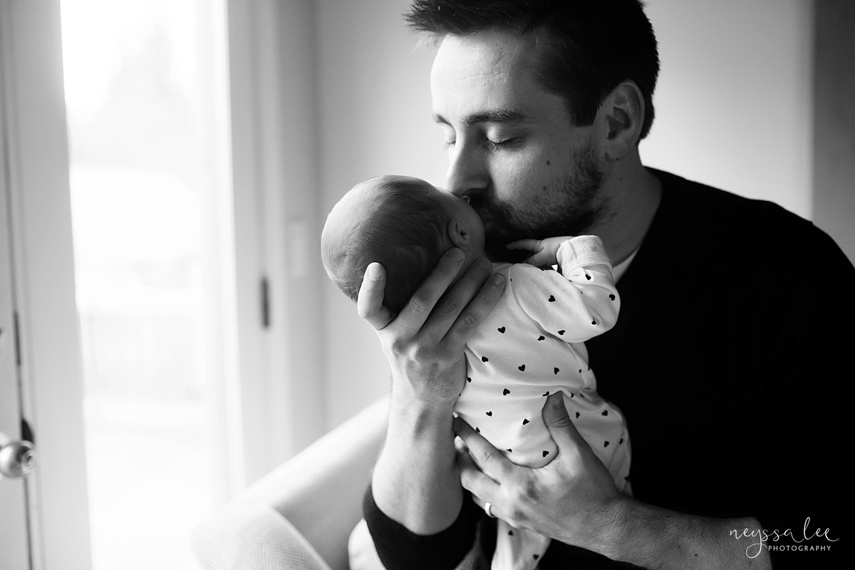 Black and white photo of dad kissing baby during Snoqualmie  in home photography session