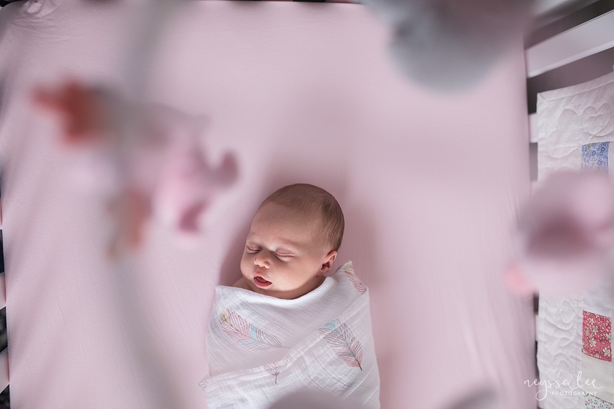 Neyssa Lee Photography, Seattle Newborn Photographer,  Newborn Photo Session Experience, Photo of newborn baby girl in crib peering through mobile