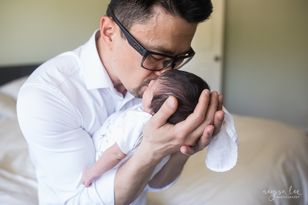 Father kissing newborn baby girl during newborn photo session