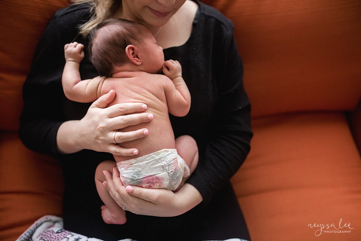 Photo of baby asleep on mom's chest in an orange chair during Snoqualmie newborn photo session