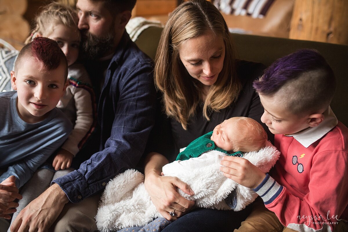 family of six on couch as oldest brother loves on baby brother during Snoqualmie newborn photo session