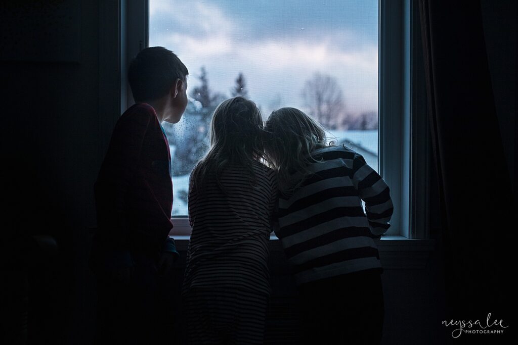 Children looking out the window at a snowy scene