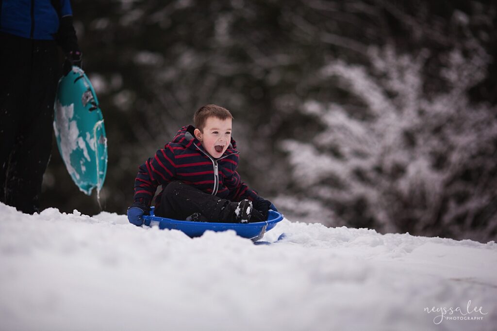 snow photo tips, boy sledding down hill on a blue sled