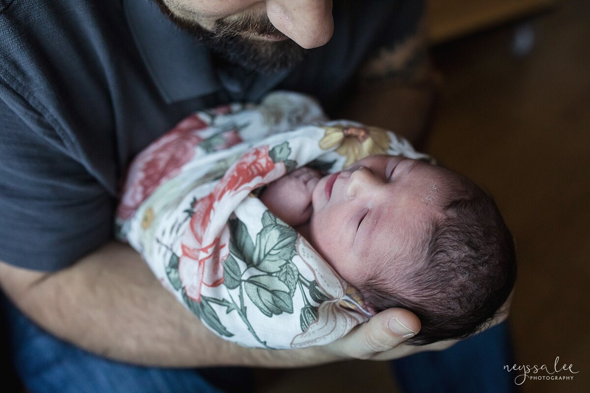 Photo of swaddled newborn baby girl in dad's arms during Swedish Hospital newborn photo session