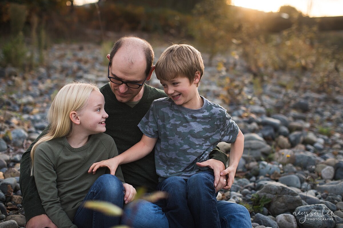 What Happens During a Lifestyle Family Photo Session, Neyssa Lee Photography, Issaquah Family Photographer, Photo of a father and his two kids sitting together on river rocks