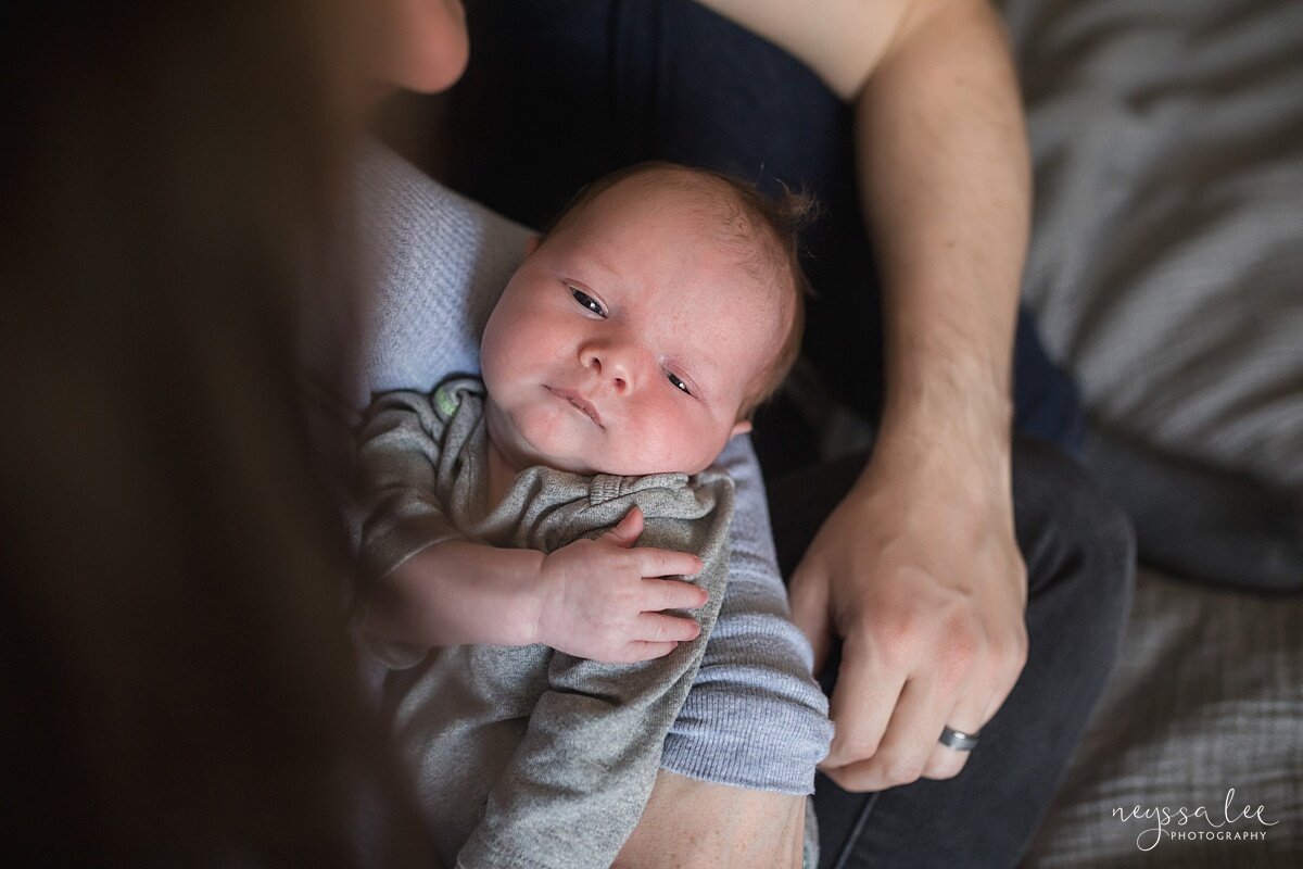 Lifestyle newborn photo with baby looking at the camera