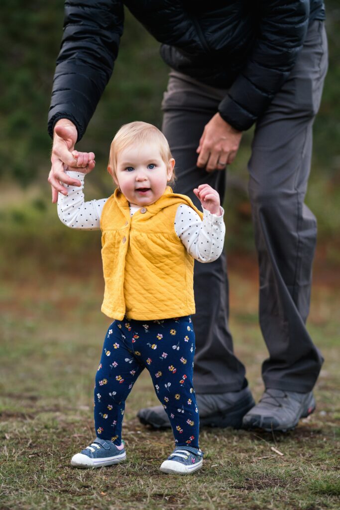 Baby girl holding dad's hand to walk during Snoqualmie pass family photo session, how to choose a photographer for your family example