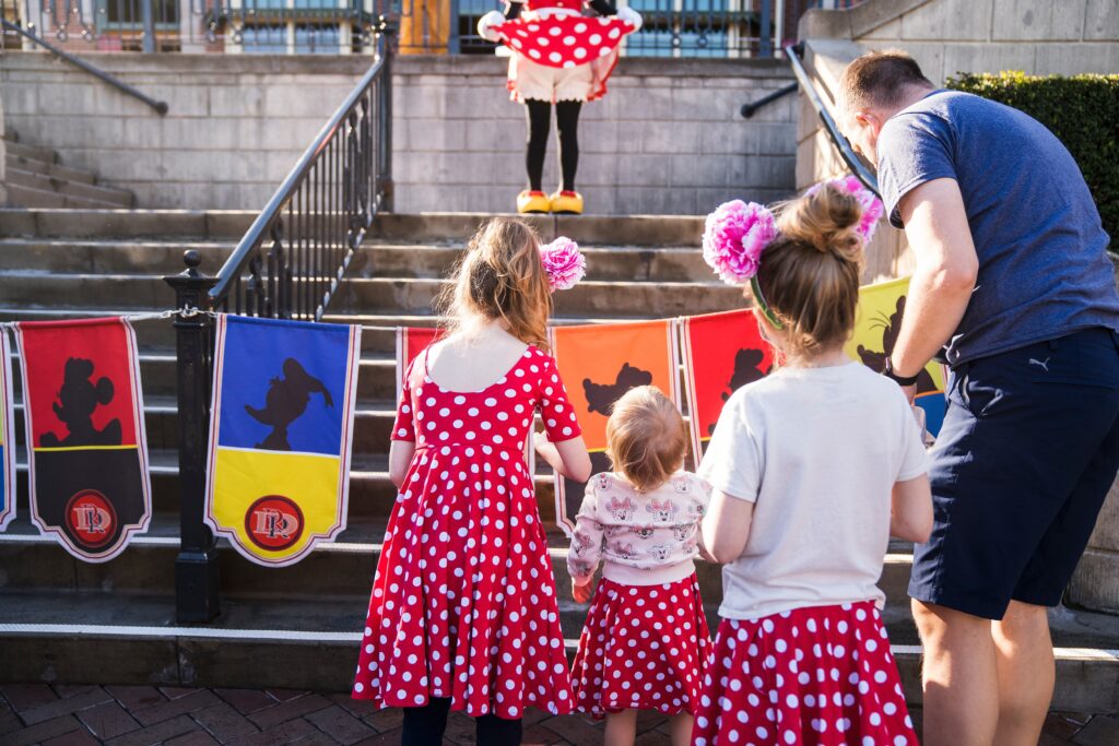 girls in red polka dot dresses like Minnie Mouse meeting Minnie in Disneyland, best lens 35mm lens