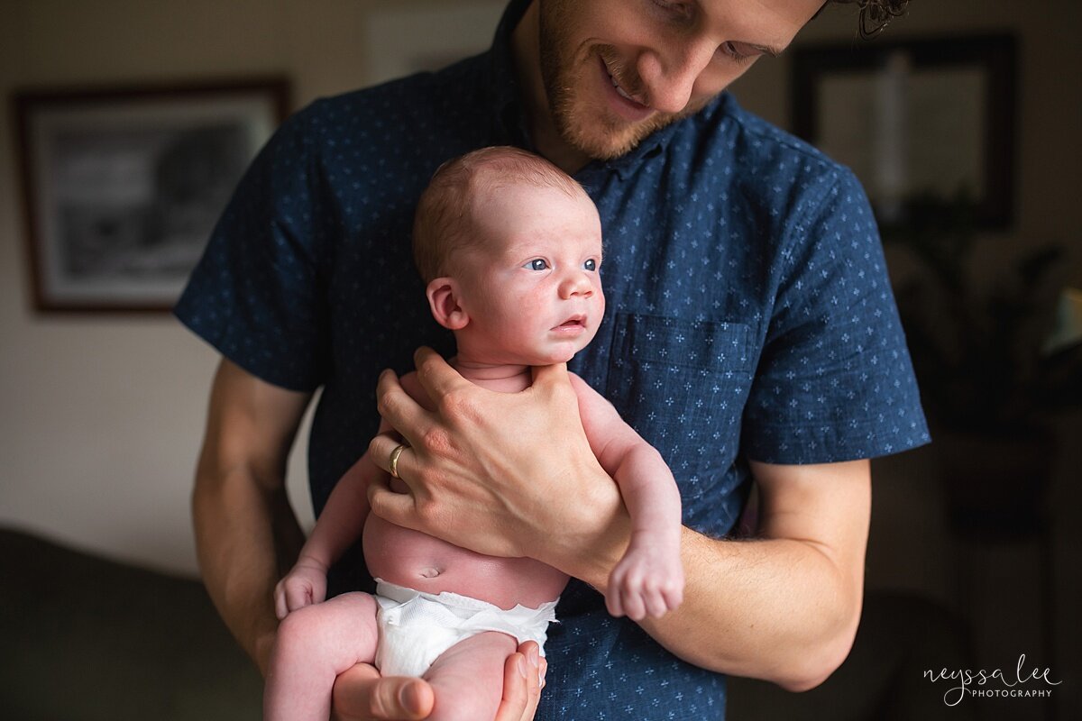 Dad holding baby against his chest so during Seattle newborn photo session