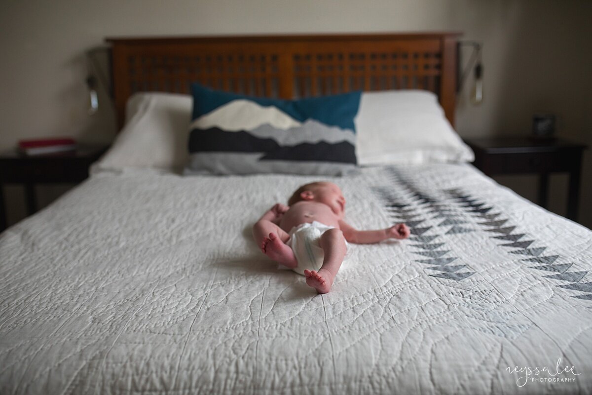 Baby photo of baby in only a diaper on a master bed during Seattle Newborn Photos