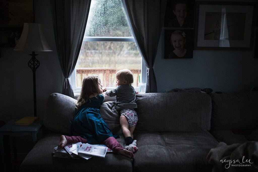 indoor low light photography of two young kids looking out the window