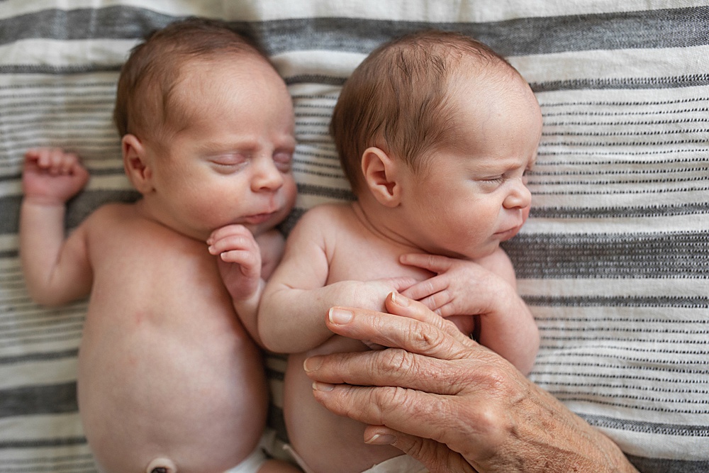 newborn twins with grandmother's hand