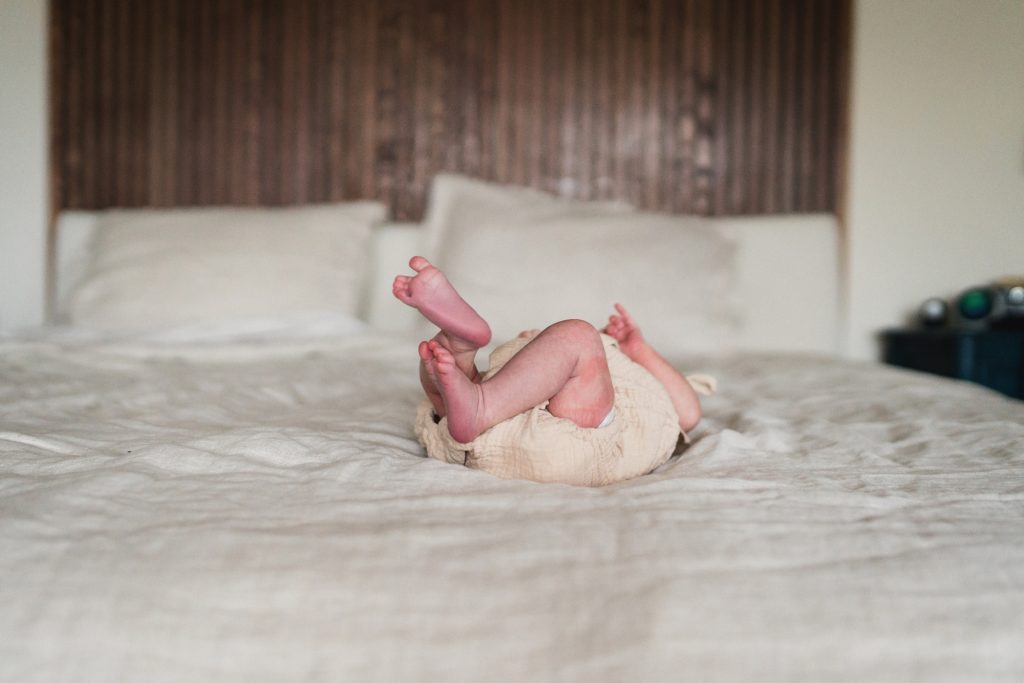newborn baby with feet in the air on master bed during Seattle newborn photo session