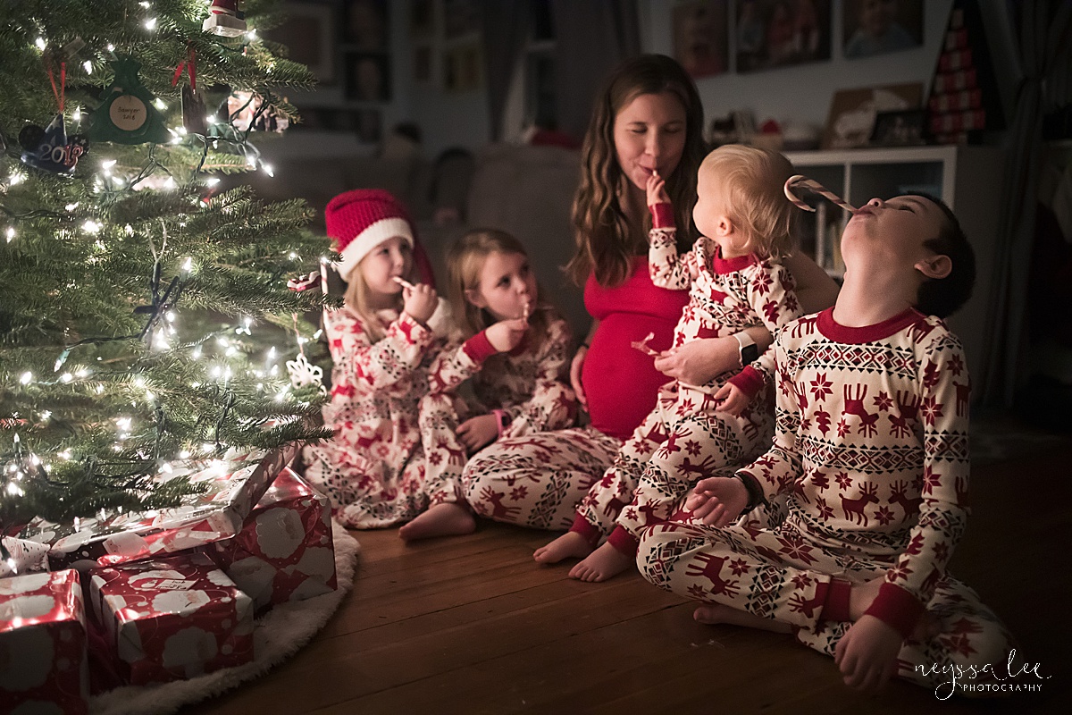 pregnant mother and four children eating candy canes by the Christmas tree