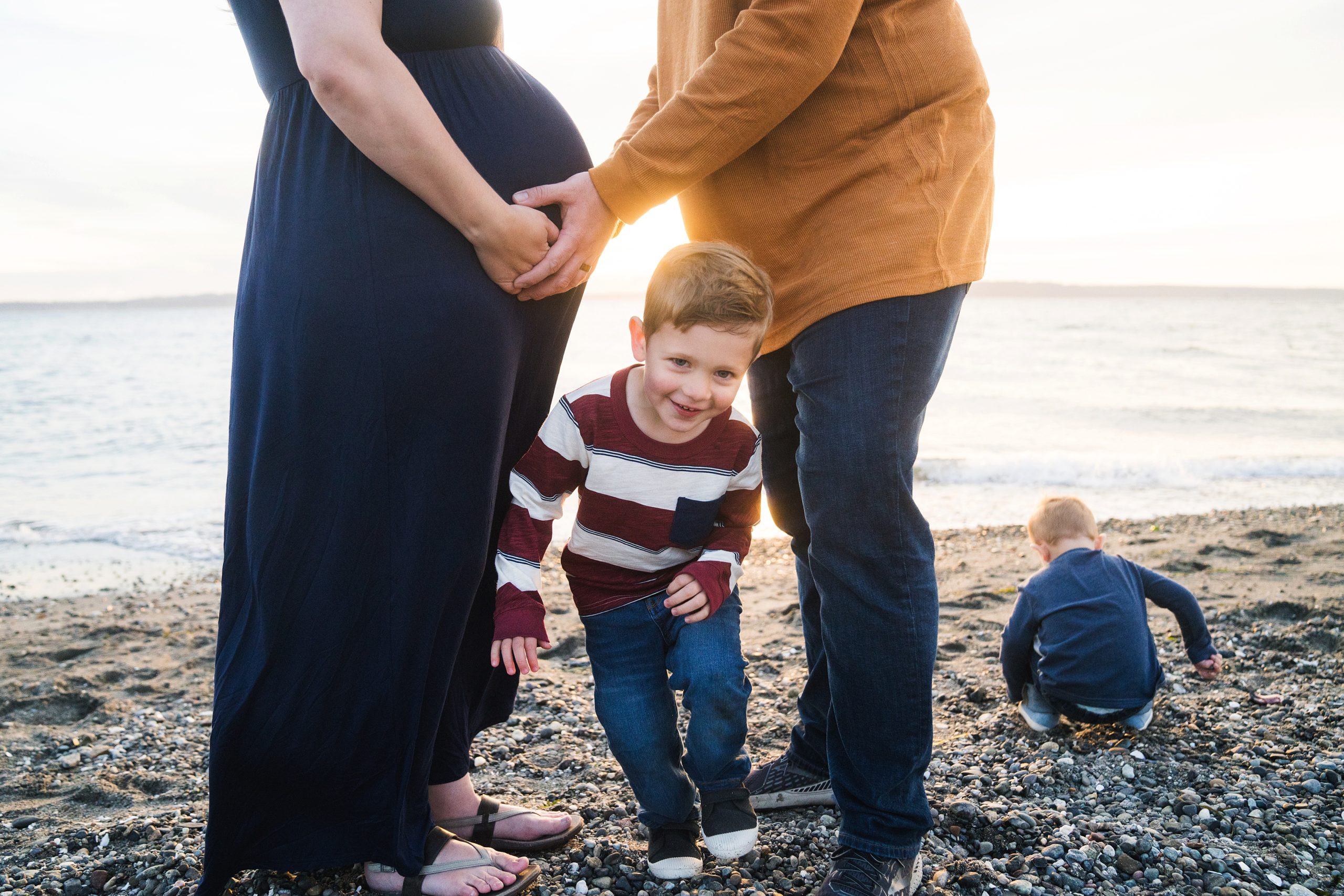 boy running between parents at the beach during Seattle maternity photos