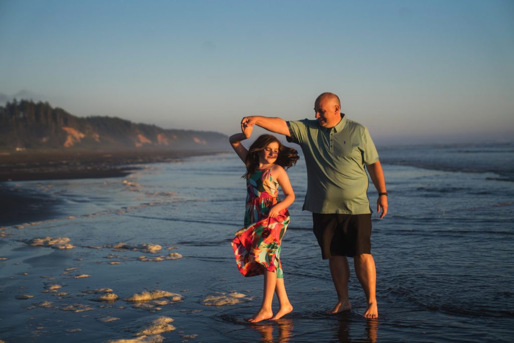 father and daughter dancing during family photos on Washington coast