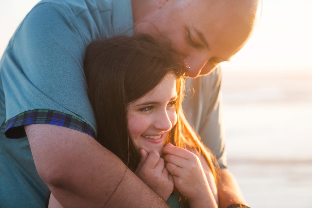 father hugging daughter with beautiful backlight during family photos in Seabrook