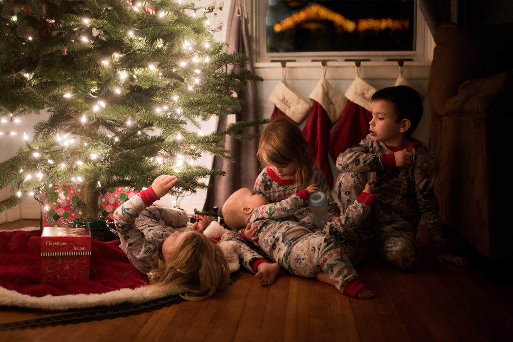 four kids lit by the Christmas tree lights