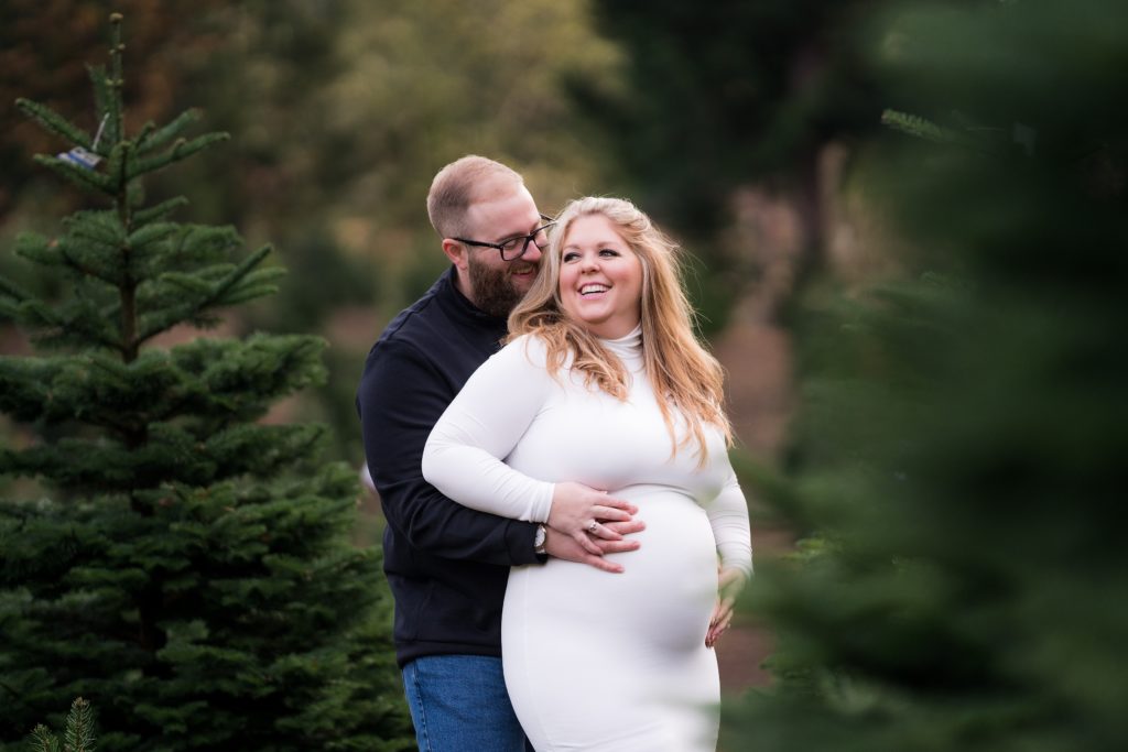 couple embracing with expecting mama in white maternity dress for Seattle maternity photo shoot
