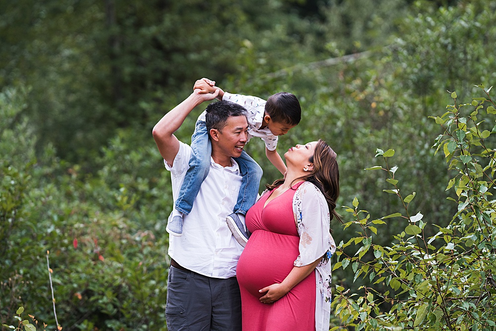 Family of three with mother in pink maternity dress for photo shoot