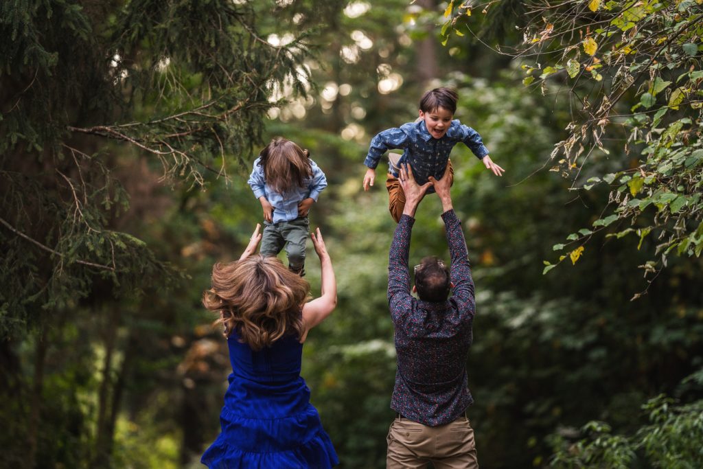 Seattle family photography at west Seattle park, parents tossing twin boys into the air