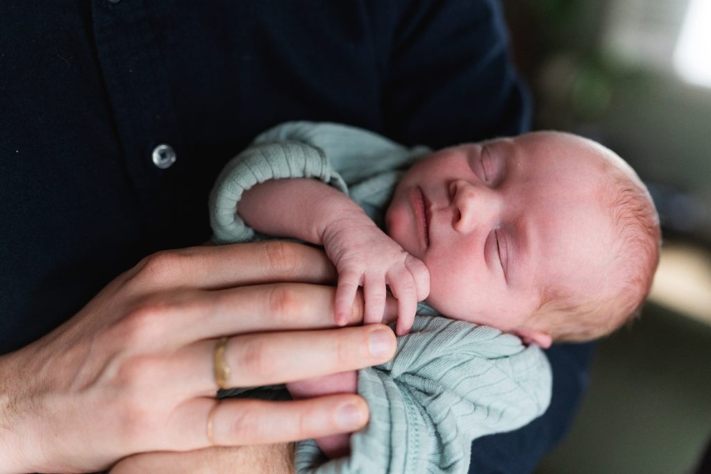 newborn baby girl holding dad's fingers