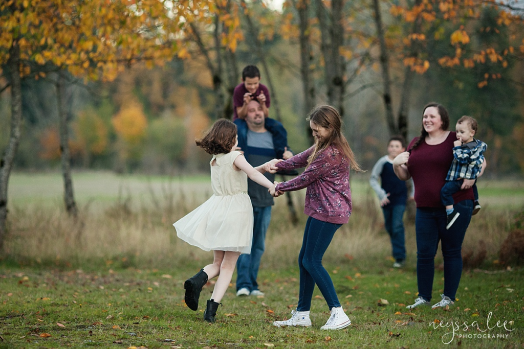 Mom, dad, and brothers observing 2 sisters twirling in a grassy field, showing what to wear for maroon and blues