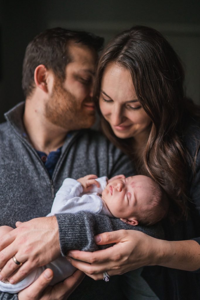 father kissing mothers head while holding newborn baby during Snoqualmie newborn photoshoot