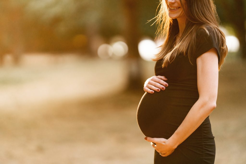 Pregnant mom framing baby bump in black dress during Lake Sammamish maternity photo session.