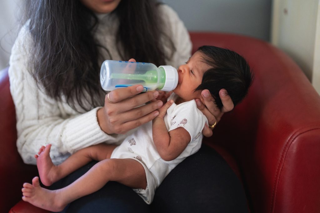 Mother feeding baby a bottle during Seattle area newborn photoshoot 
