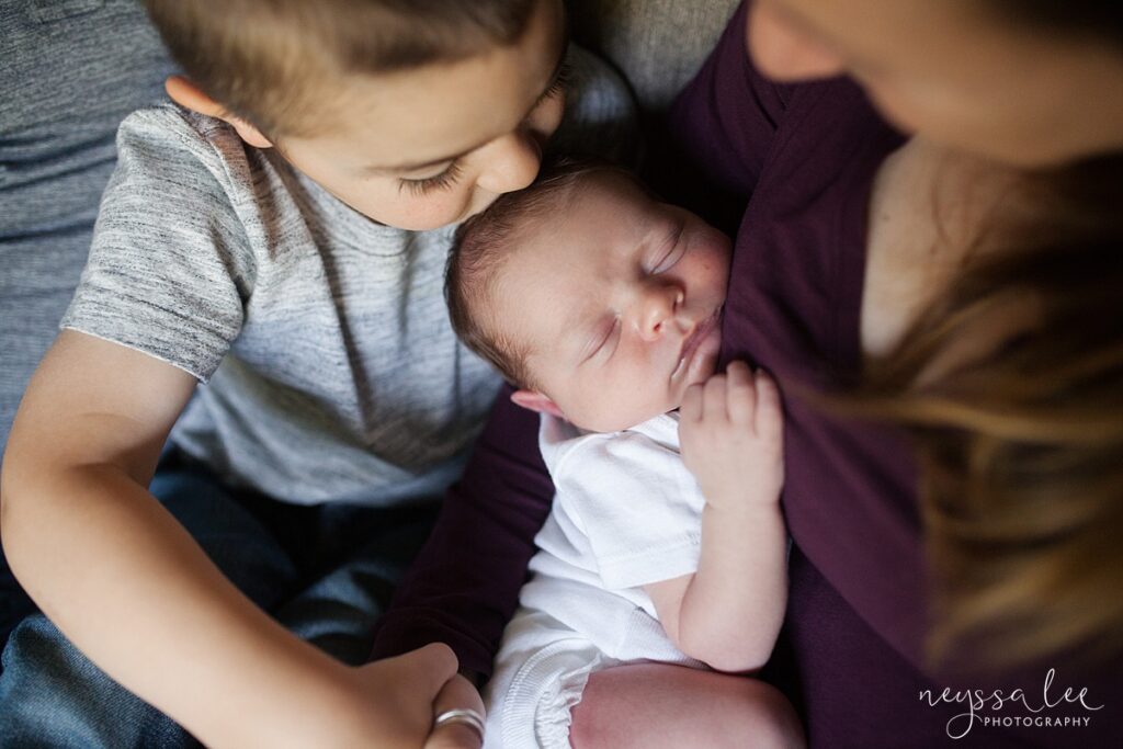Big brother kissing newborn brother's head during Seattle newborn photography session