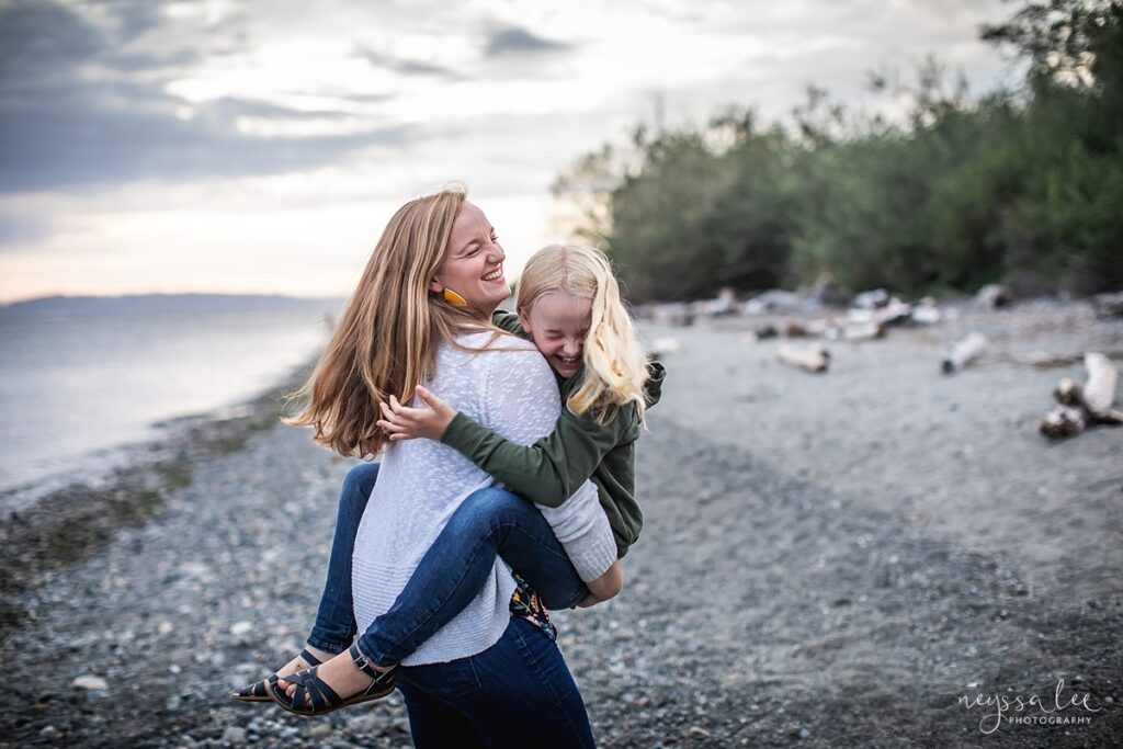 Mother holding and twirling with daughter during Seattle beach family photography session