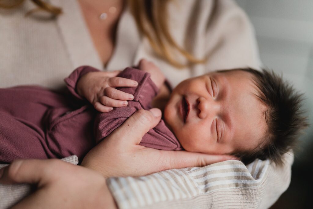 Newborn baby in parent's arm as example of why you want an in home session not a newborn photography studio session