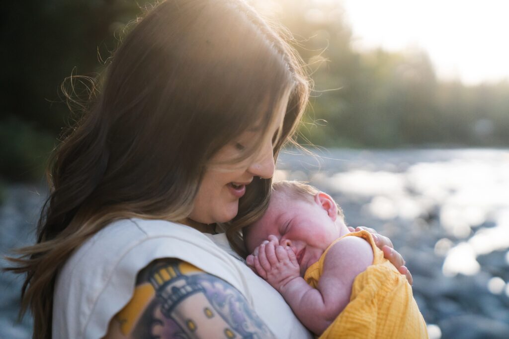 Mother holding baby girl in golden backlight during lifestyle family photography session