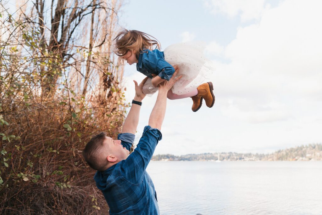 Father tosses daughter into the air during Seattle area family photo session